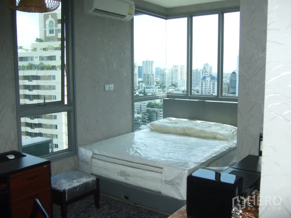 Condominium for rent or sale in Watthana, Bangkok - Corner bedroom with floor-to-ceiling windows and panoramic Bangkok skyline views.