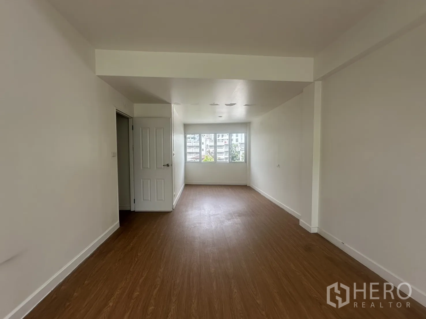 โฮมออฟฟิศ for rent in Watthana, Bangkok - ห้องชั้นบนสุดพื้นลายไม้พร้อมหน้าต่างที่ปลายห้อง.