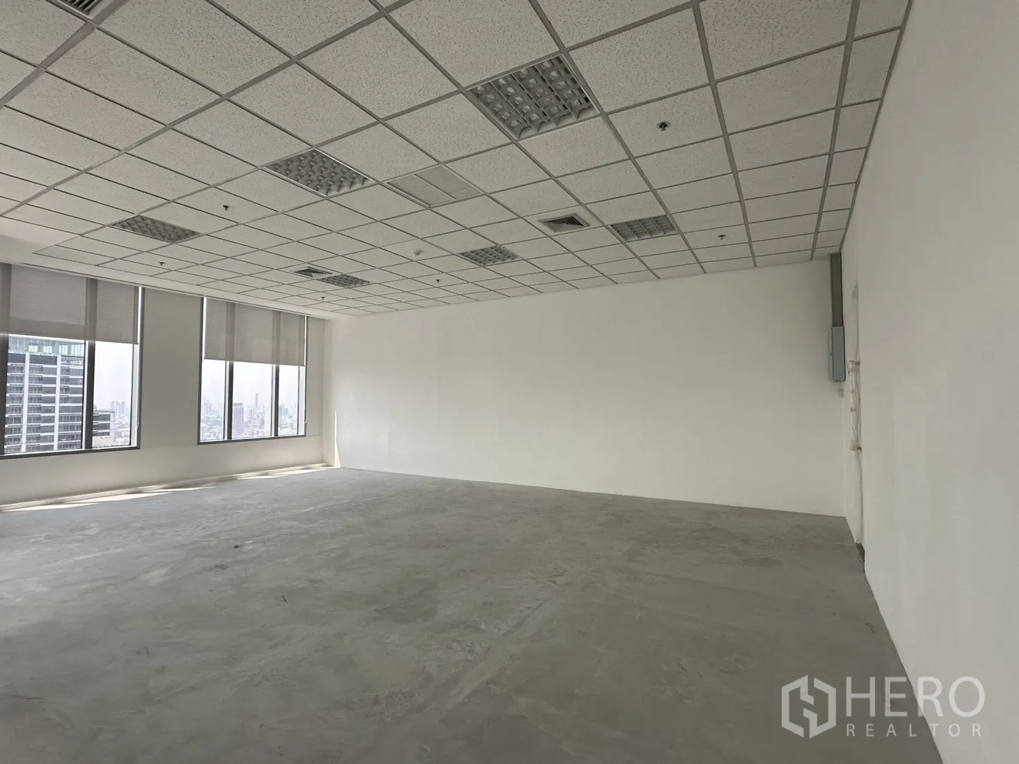 Office Space for rent in Khlong Toei, Bangkok - Open-plan office with white walls, suspended ceiling, large windows with blinds, and city views.