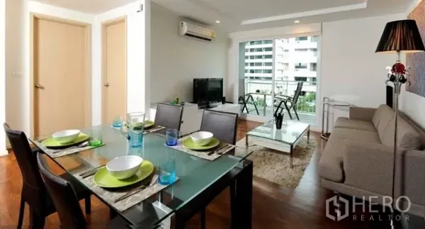 公寓 出租或出售在Khlong Toei, Bangkok - 开放式客餐厅，配沙发与玻璃餐桌，连接阳台可观城市景观的素坤逸公寓。