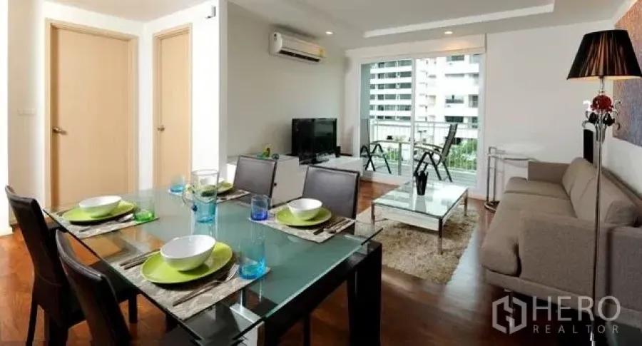 公寓 出租或出售在Khlong Toei, Bangkok - 开放式客餐厅，配沙发与玻璃餐桌，连接阳台可观城市景观的素坤逸公寓。