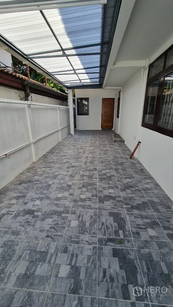 Detached House for rent in Lat Phrao, Bangkok - Covered tiled side terrace or carport with a translucent roof beside the house.