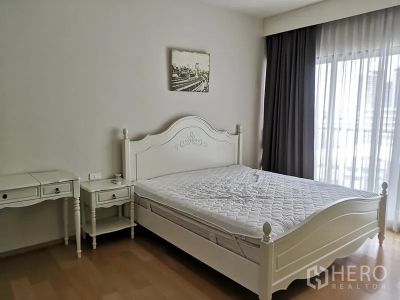 Condominium for rent or sale in Phaya Thai, Bangkok - Master bedroom with classic white bedframe and large curtained windows.