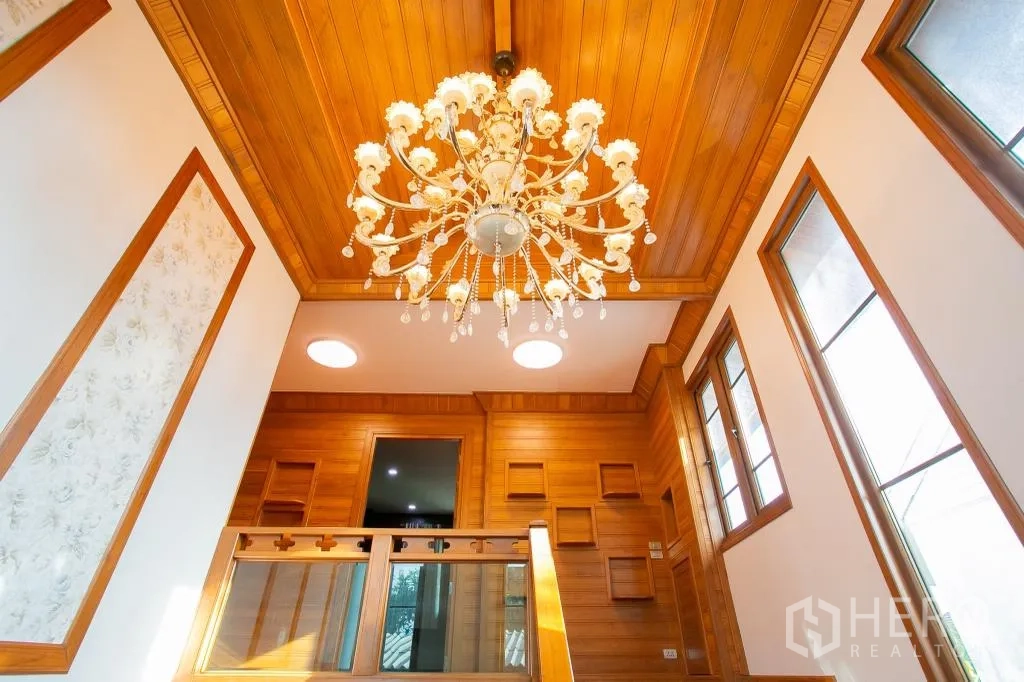 独栋房屋 for rent or sale in Huai Khwang, Bangkok - 楼梯间上方华丽吊灯，木质天花与高窗。