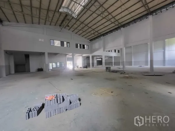 Factory for rent or sale in Samut Prakan - Spacious factory hall with high steel truss roof, concrete floor and internal windows.