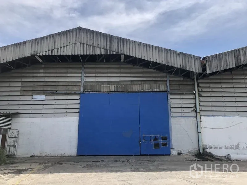 Warehouse for rent in Bang Phli, Samut Prakan - Industrial warehouse facade with corrugated metal cladding and a large blue sliding door.