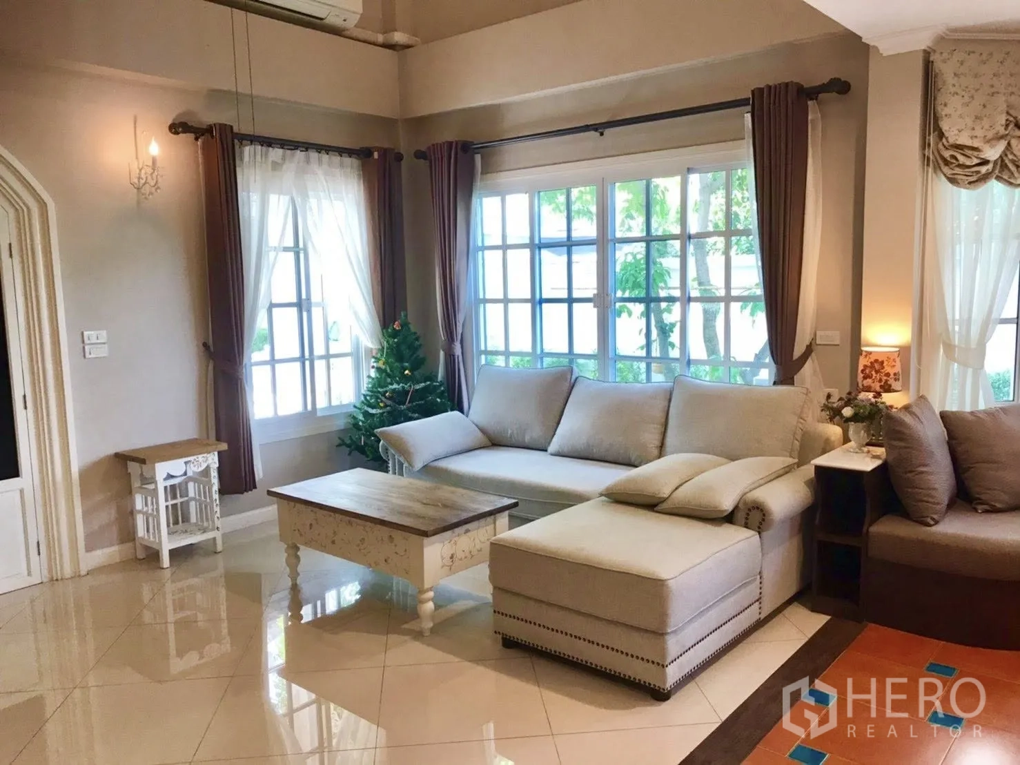 บ้านเดี่ยว for rent in Mueang Samut Prakan, Samut Prakan - ห้องนั่งเล่นอบอุ่นพร้อมโซฟาตัวแอล โต๊ะกลาง และหน้าต่างบานใหญ่มีผ้าม่าน