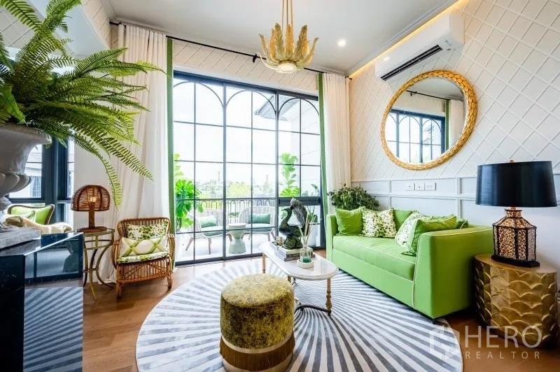 Detached House for sale in Bang Kapi, Bangkok - Bright lounge with green sofa and full-height arched windows opening to a balcony.