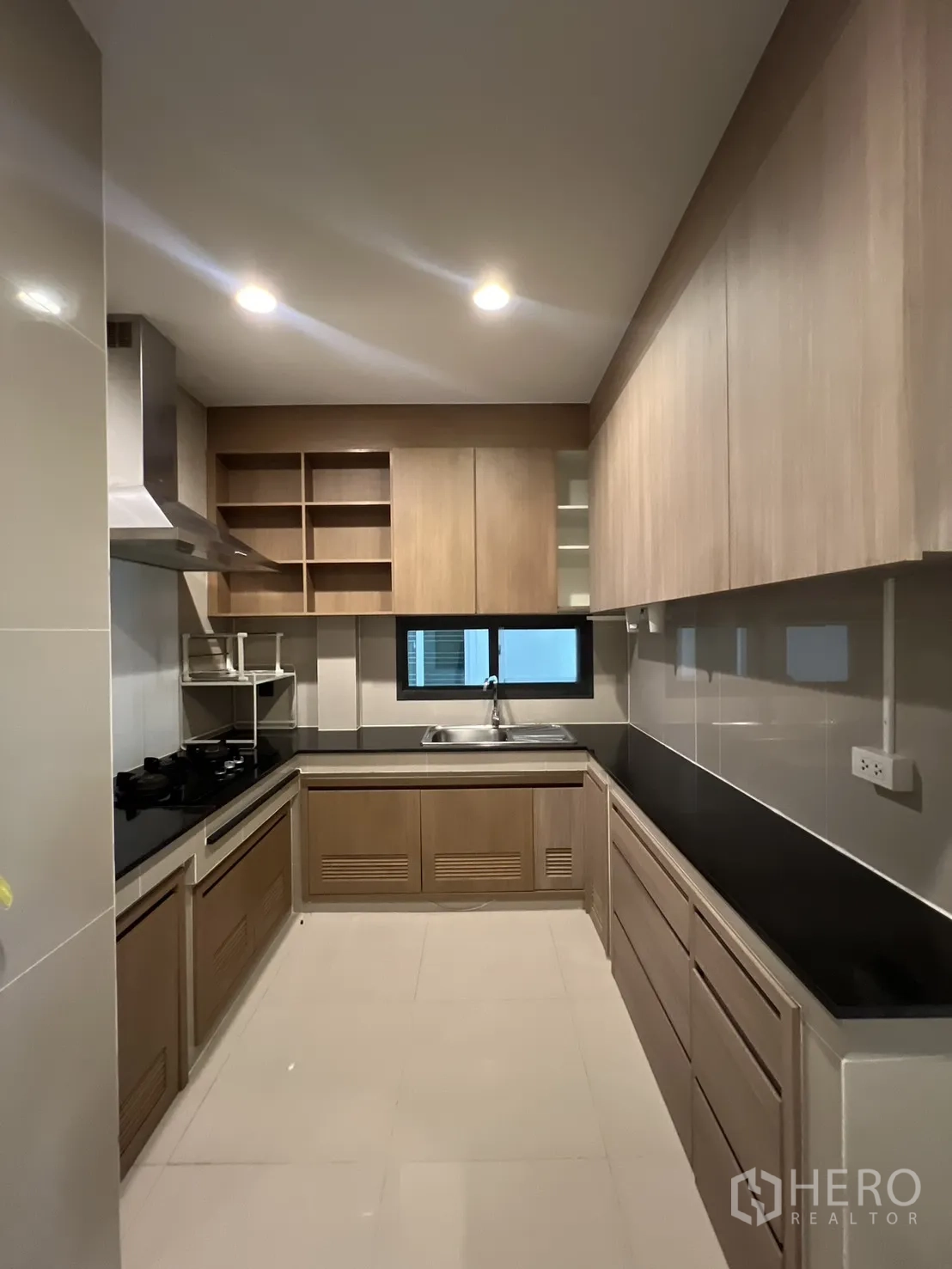 Detached House for sale in Bang Kapi, Bangkok - Fitted kitchen with wood cabinetry, gas hob, hood, and window.