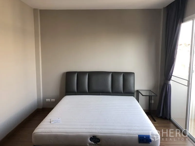 Townhouse for rent in Yan Nawa, Bangkok - Master bedroom with upholstered headboard, large window and balcony access.