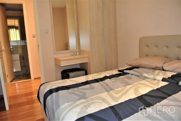 Condominium for rent in Watthana, Bangkok - Cozy bedroom with built-in wardrobe, vanity and ensuite access, featuring warm wood floors and soft lighting.