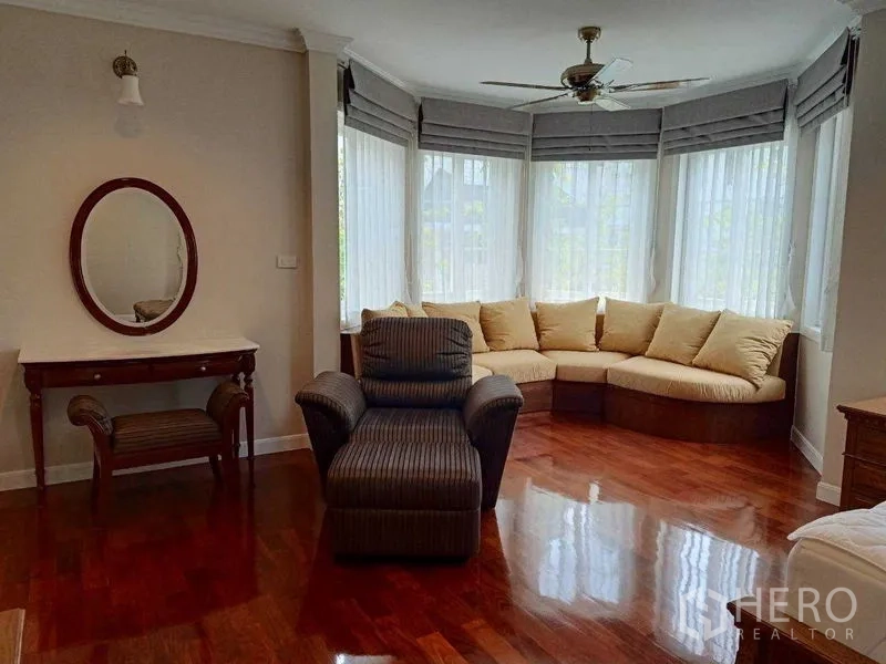 บ้าน ให้เช่าในBang Na, Bangkok - มุมนั่งเล่นหน้าต่างแบบเบย์ โซฟาโค้งบิวท์อิน เก้าอี้อาร์มแชร์ และพื้นไม้เงา