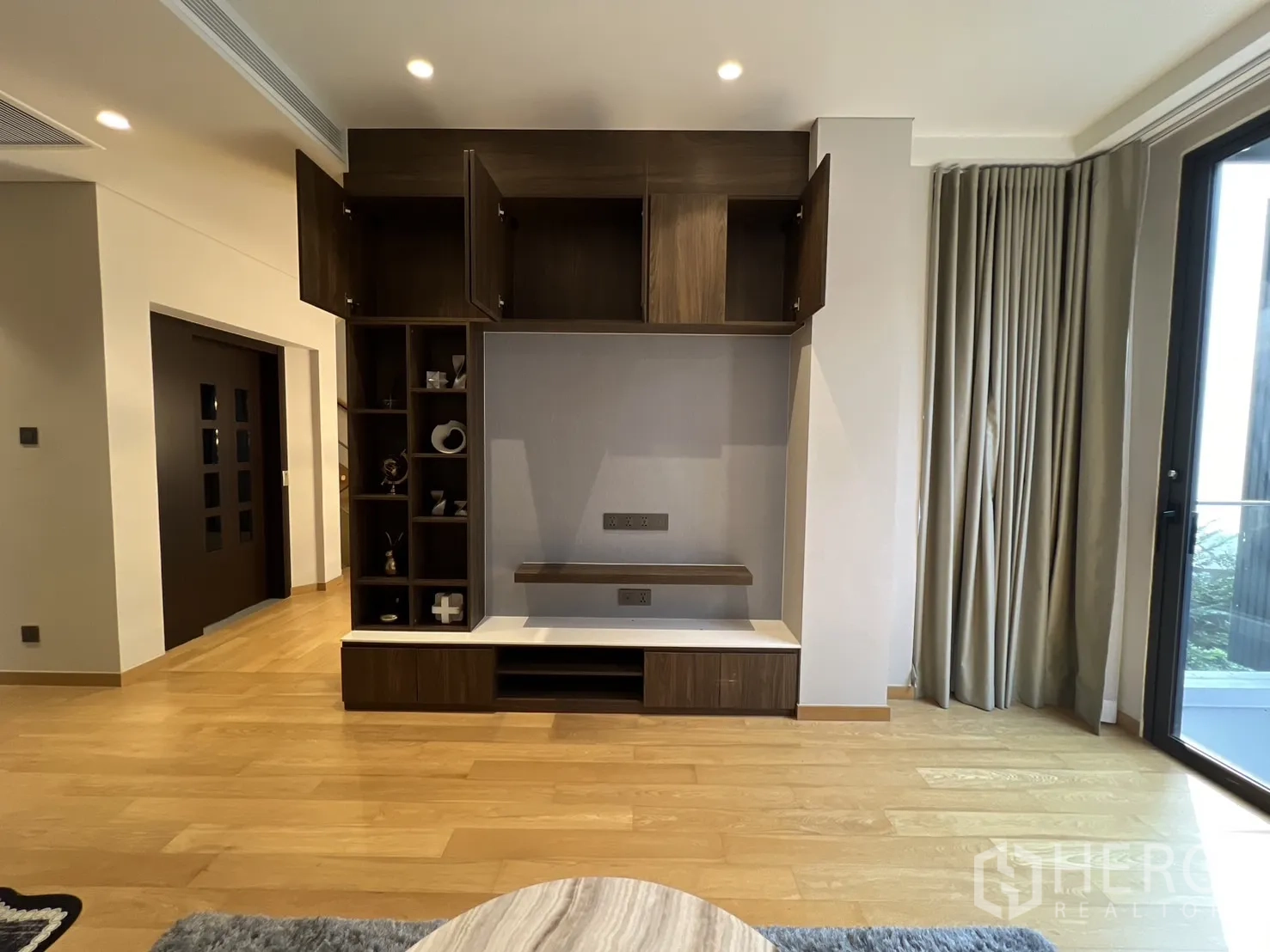 Detached House for rent in Suan Luang, Bangkok - Media wall cabinetry with open shelving and balcony access.