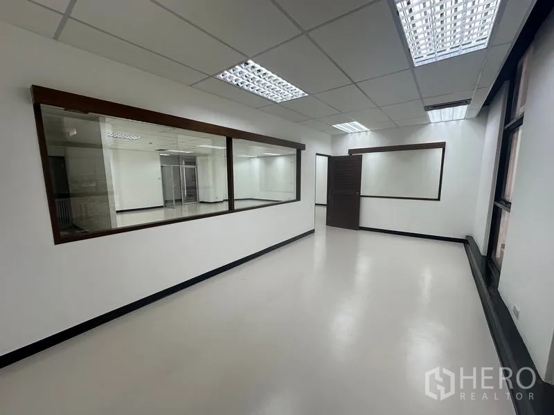 Office Space for rent - Private office with large internal observation windows and fluorescent lighting.