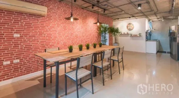 公寓 出租在Watthana, Bangkok - 开放式餐区，长木桌、吊灯与红砖特色墙