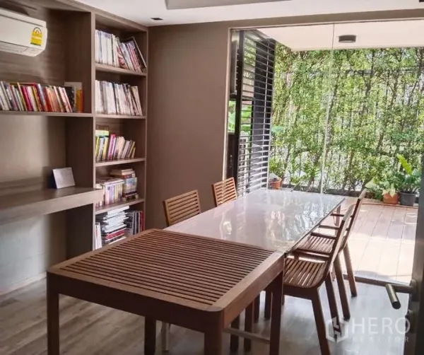 Condominium for rent - Reading room with built-in bookshelves and a long table facing greenery.
