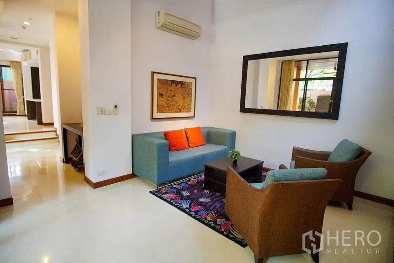 ทาวน์เฮาส์ ให้เช่าในWatthana, Bangkok - ห้องรับแขกอบอุ่น โซฟาสีฟ้า เก้าอี้หวาย และพรมสีสัน