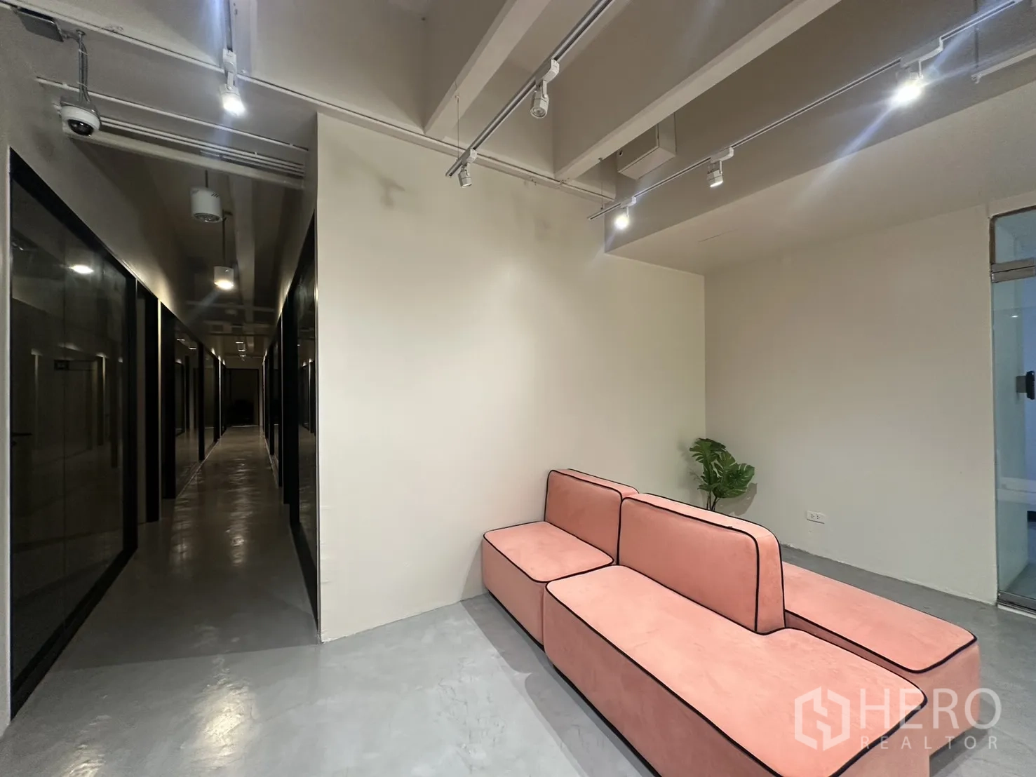Office Space for rent in Bang Rak, Bangkok - Breakout lounge with pink modular sofa, track lighting, and a potted plant.