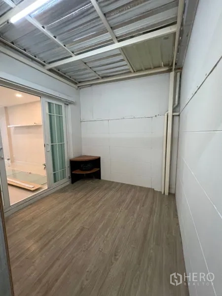 Home Office for rent - Covered back utility area with sliding door, wood-look floor, and exposed roof structure.