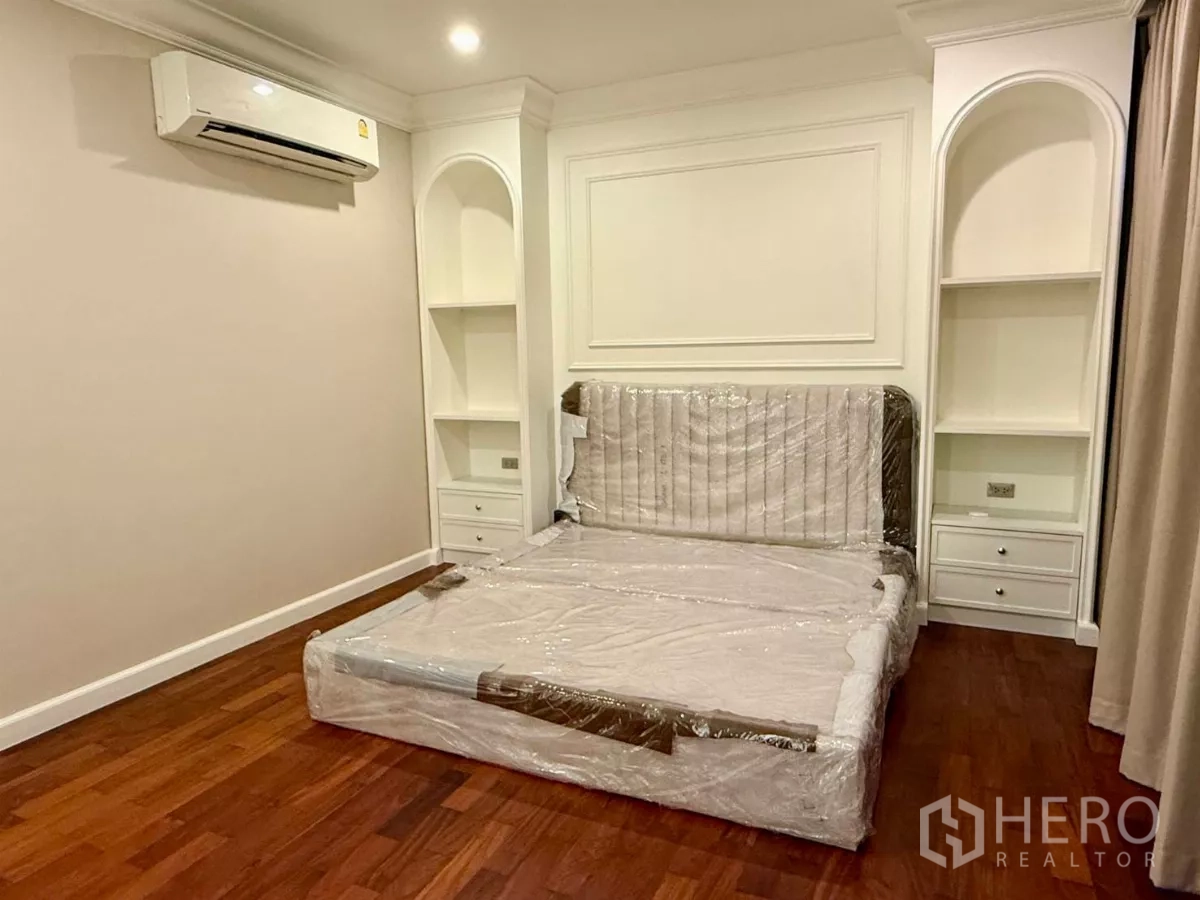Townhouse for rent in Bang Kho Laem, Bangkok - Guest bedroom with arched built-in shelves and a wrapped bed on hardwood flooring