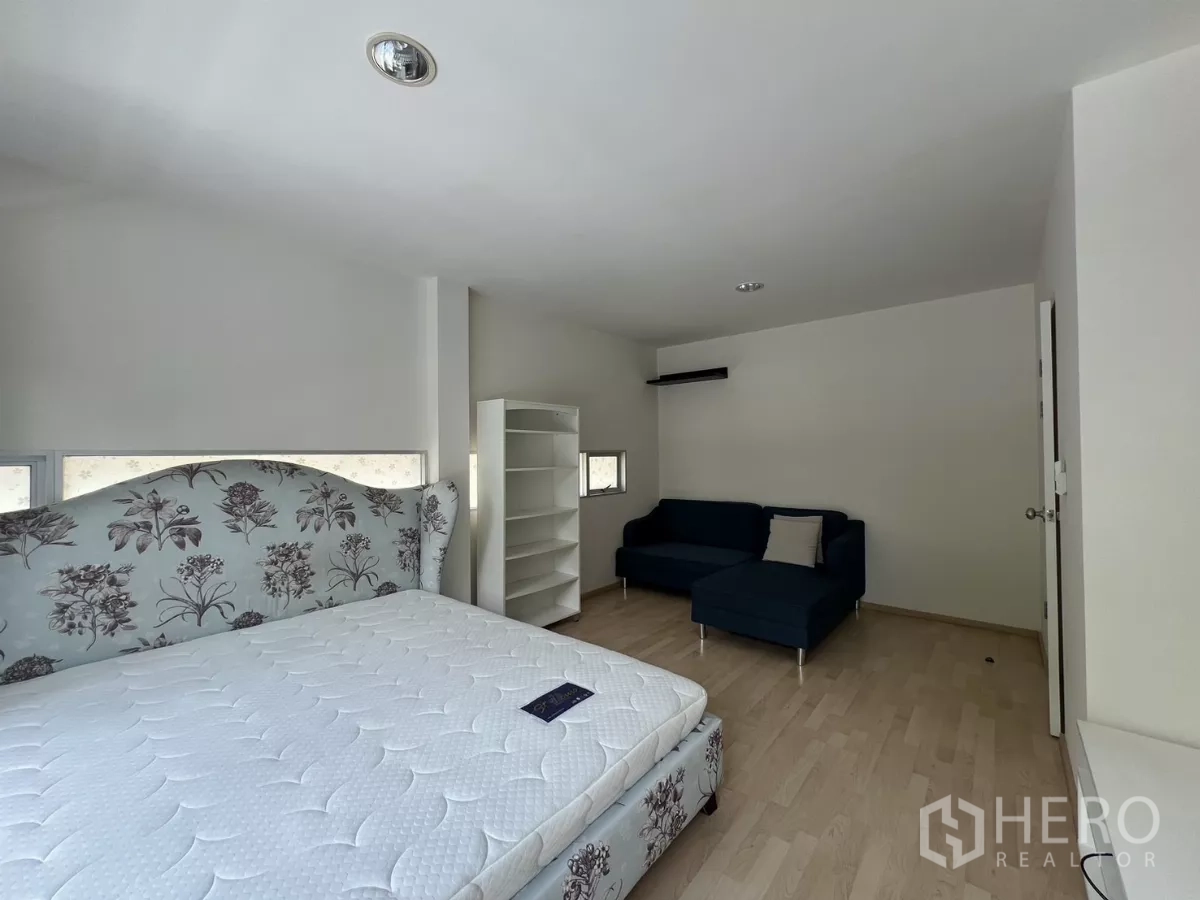 Townhouse for rent in Suan Luang, Bangkok - Master bedroom view with bed near wide balcony doors.