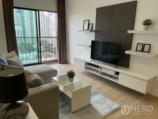 Condominium for rent in Bangkok - Living area opening to a balcony with floor-to-ceiling glass and city skyline view.