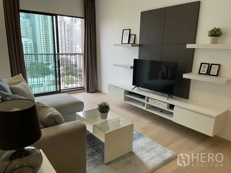 Condominium for rent in Bangkok - Living area opening to a balcony with floor-to-ceiling glass and city skyline view.