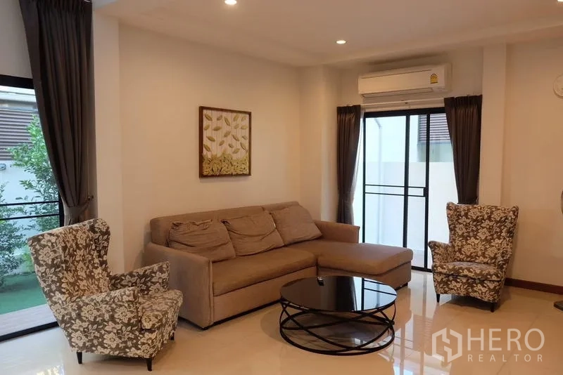 独立式住宅 出租在Bang Phli, Samut Prakan - 宽敞客厅，沙发与扶手椅，通往阳台/花园的门