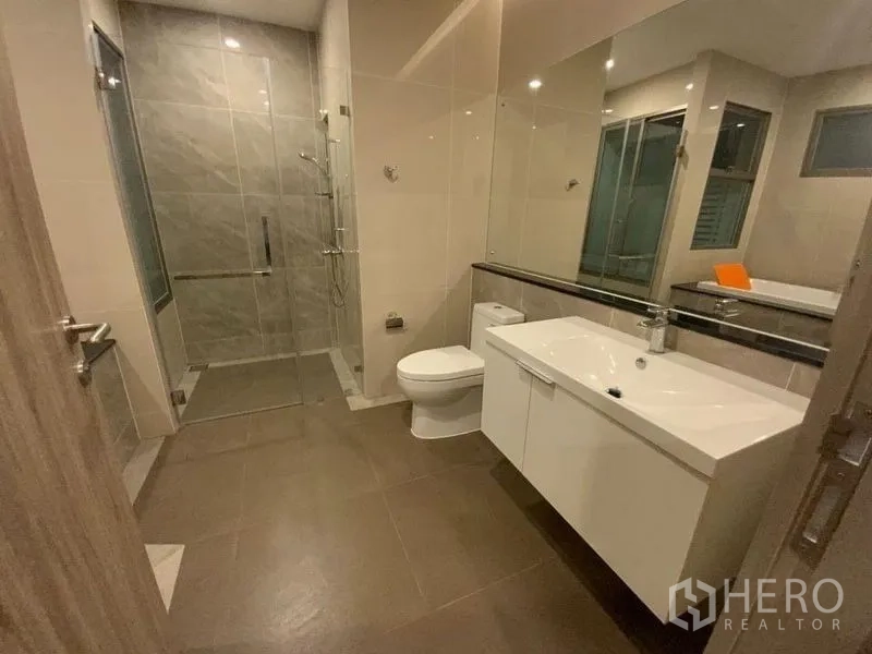 Townhouse for rent in Prawet, Bangkok - Spacious bathroom with vanity, toilet and glass-enclosed shower.