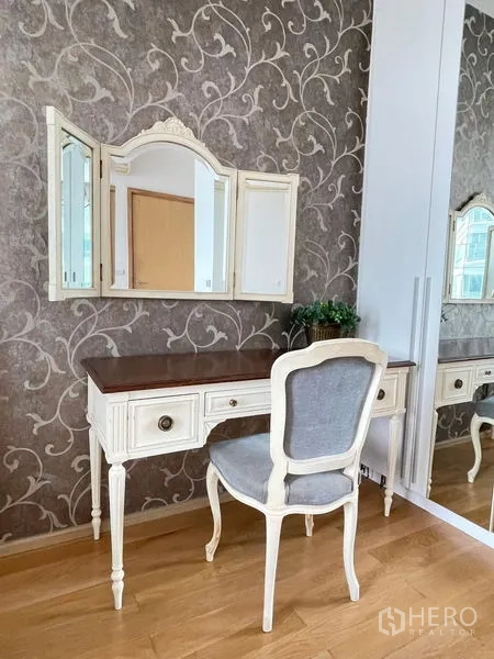 Condominium for rent in Watthana, Bangkok - Elegant vanity desk with tri-fold mirror against patterned wallpaper.