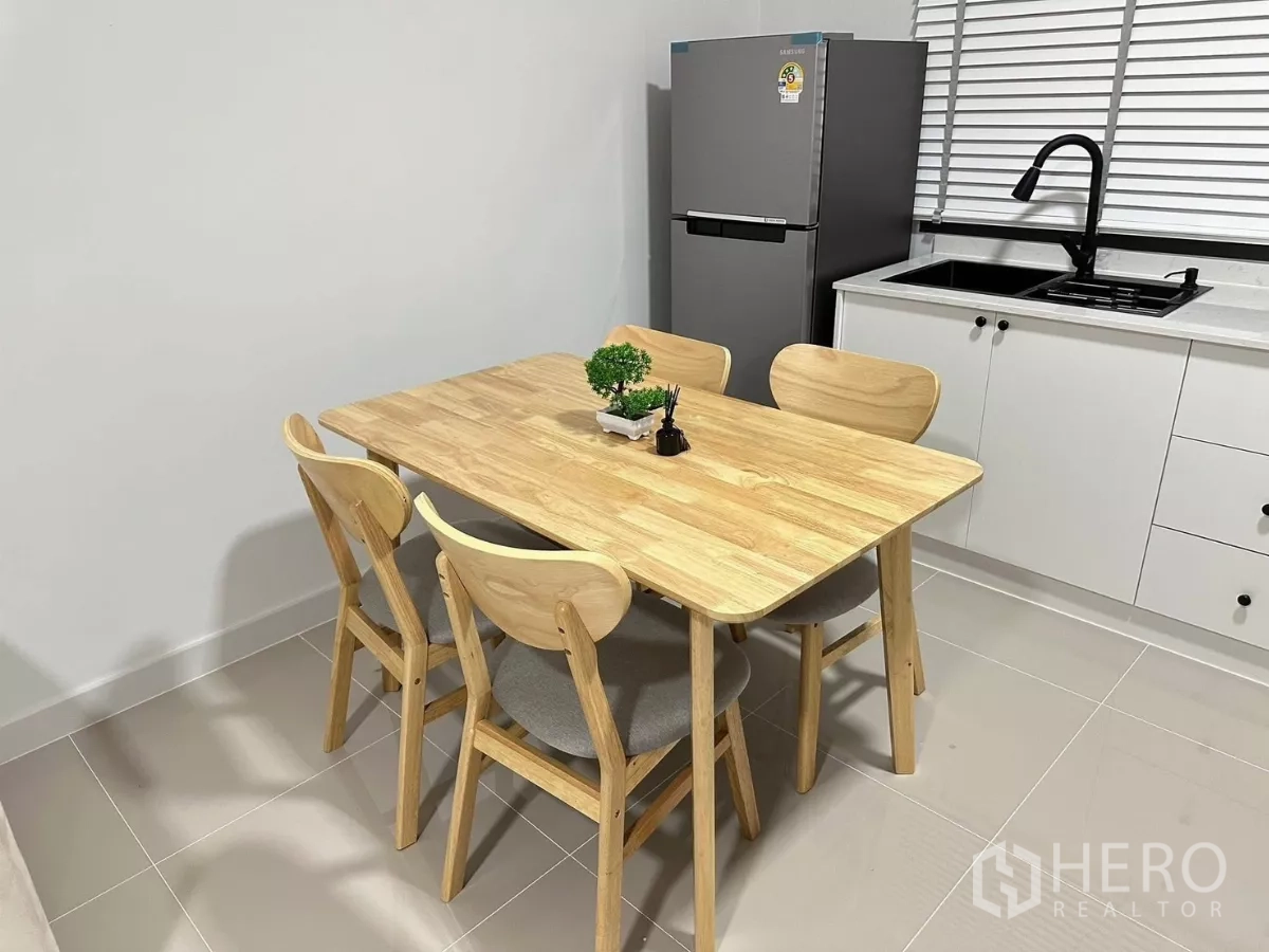 Townhouse for rent in Bang Phli, Samut Prakan - Close‑up of the wooden dining set beside a refrigerator and window sink.