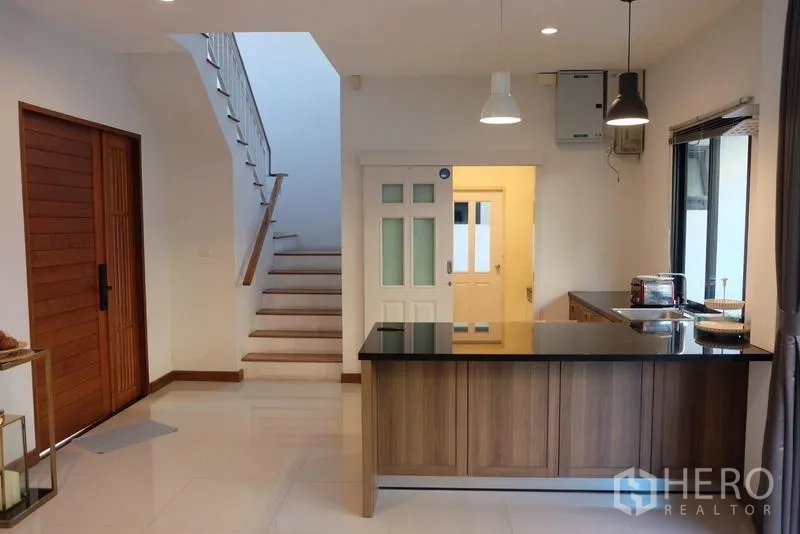 独立式住宅 出租在Bang Phli, Samut Prakan - 开放式厨房，中岛台与吊灯，可见楼梯
