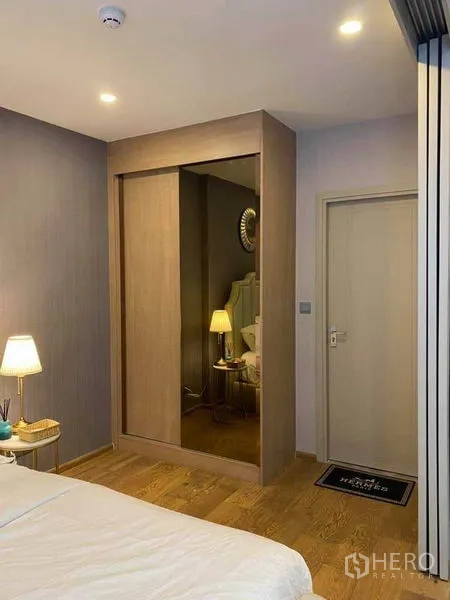 公寓 出售在Ratchathewi, Bangkok - 卧室一角带内置推拉门衣柜和通往浴室的门。