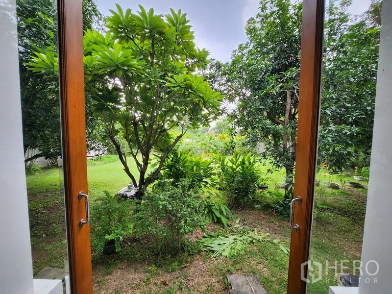 บ้าน ให้เช่าในPrawet, Bangkok - วิวสวนผ่านประตูบานเฟรนช์ เห็นต้นไม้ทรอปิคัลและสนามหญ้า