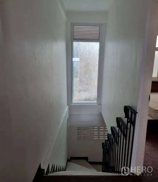 Shophouse for rent in Watthana, Bangkok - Stairwell with metal handrail and tall window bringing in natural light.