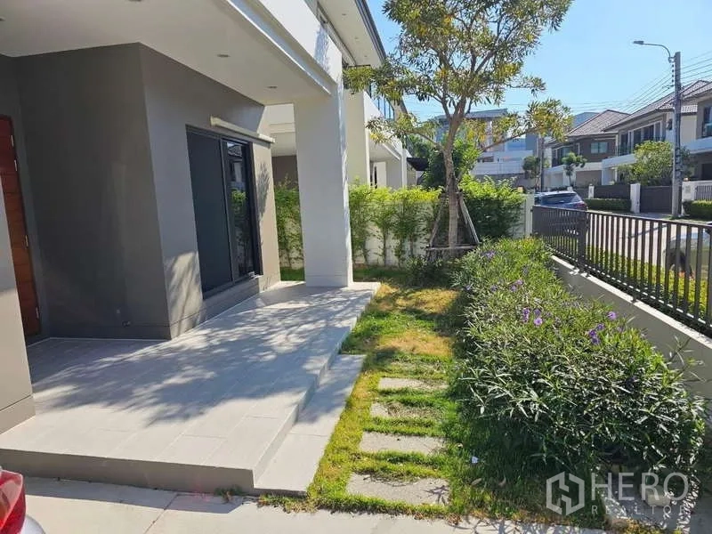 Detached House for rent in Bang Phli, Samut Prakan - Front terrace with small lawn, stepping-stone path and metal fence along the street.
