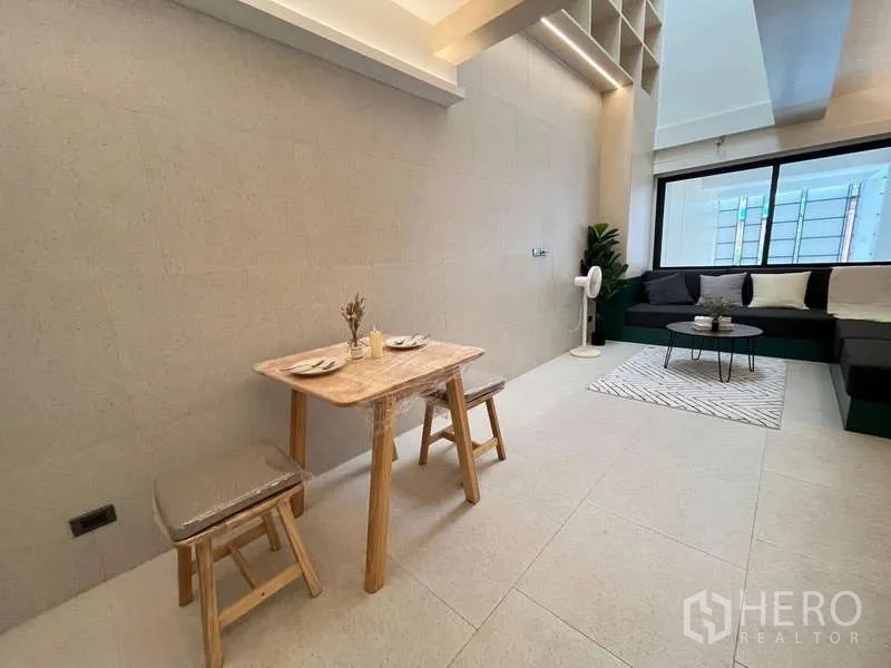 联排别墅 出售在Khlong Toei, Bangkok - 紧凑餐区，木质餐桌与高脚凳，邻近客厅。