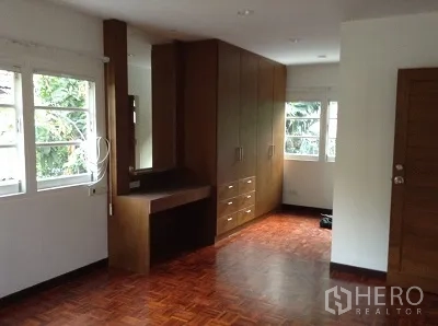 独立式住宅 出租在Ratchathewi, Bangkok - 卧室铺拼花木地板，转角窗户，配内置衣柜与梳妆台。