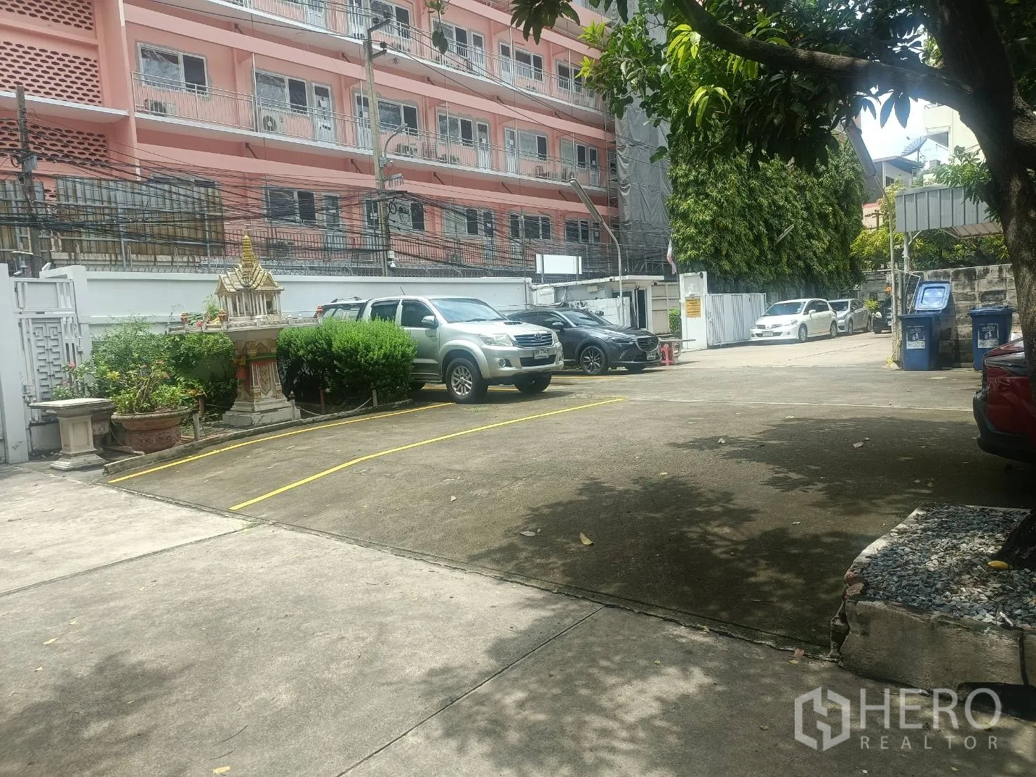 独立式住宅 出租在Bang Rak, Bangkok - 宽阔的水泥停车庭院，划线车位与安全大门，周边为城市建筑。