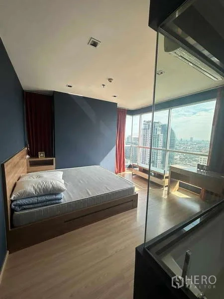 Condominium for sale in Phaya Thai, Bangkok - Corner bedroom with bed and desk facing panoramic city views through full‑height windows and balcony.