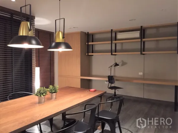 公寓 出租或出售在Watthana, Bangkok - 餐桌旁内置工作区与墙面搁架，黑金吊灯点缀空间。