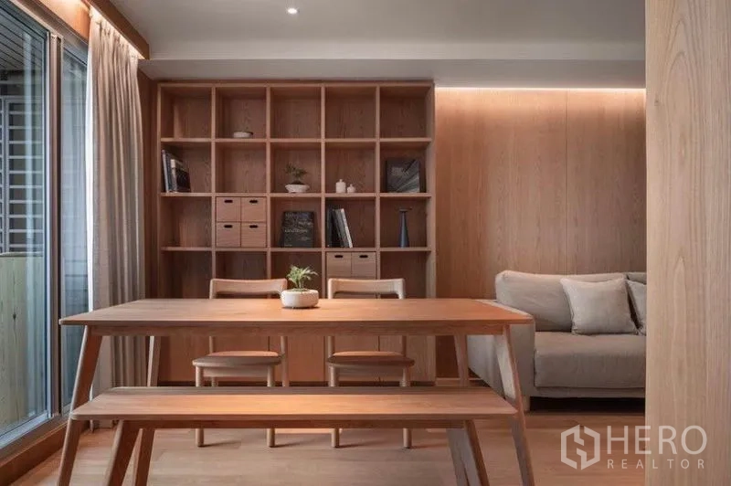 Condominium for rent in Phaya Thai, Bangkok - Close-up of dining table set against a floor-to-ceiling built-in bookshelf and sofa.