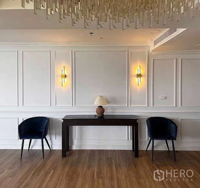 Condominium for rent or sale in Khlong Toei, Bangkok - Sitting nook with two blue chairs, console table and decorative lights