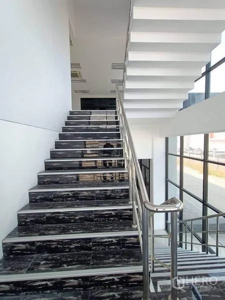 Warehouse for rent or sale in Pathum Thani - Staircase with stainless handrail in a double-height glass atrium.