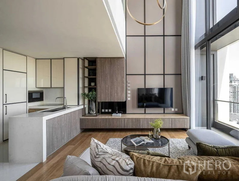 Condominium for sale in Khlong Toei, Bangkok - Contemporary living room with double-height ceiling, sleek kitchen island, media wall, and large windows.