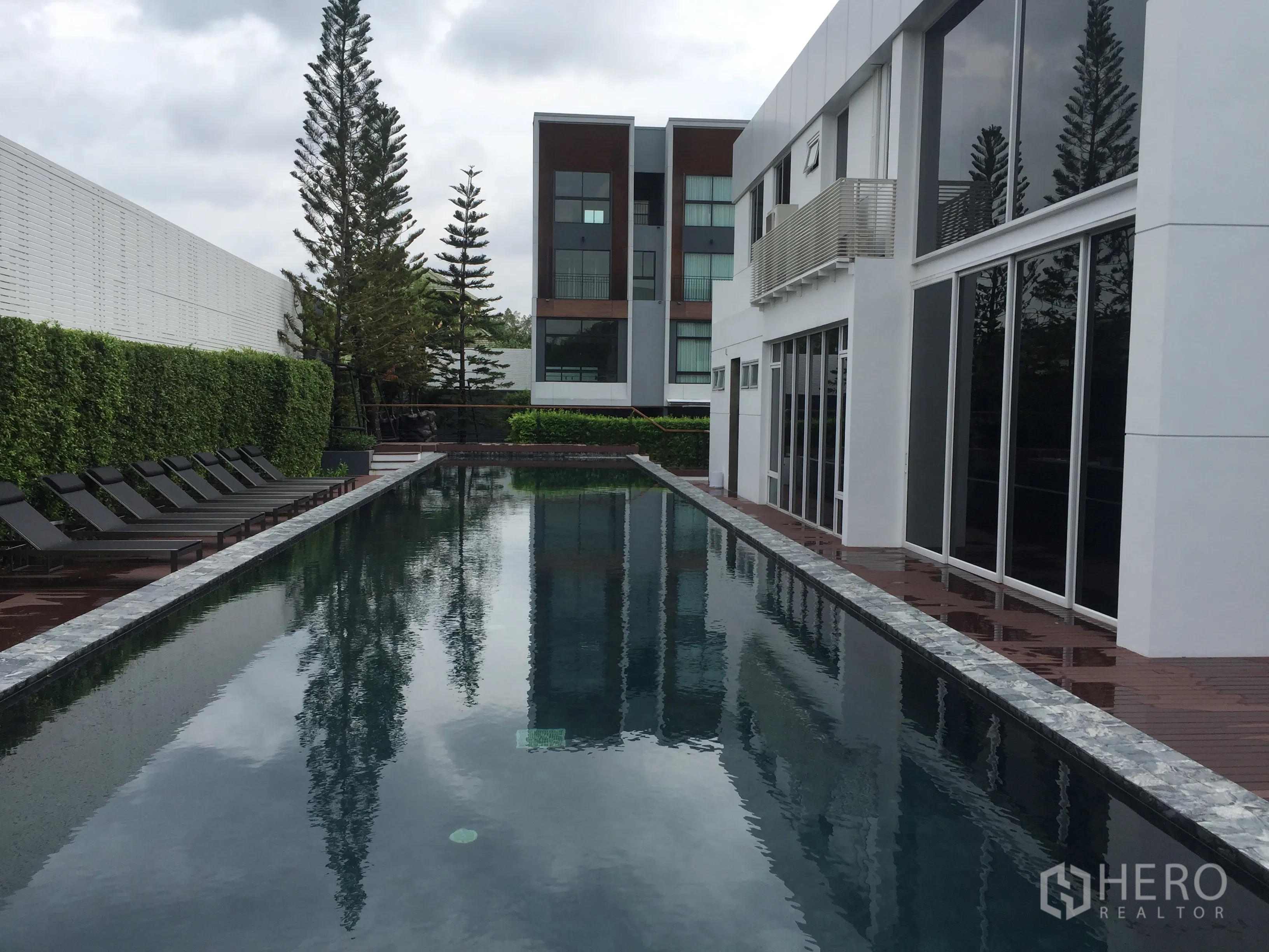 Townhouse for rent or sale in Suan Luang, Bangkok - Long lap swimming pool with sun loungers beside the clubhouse.