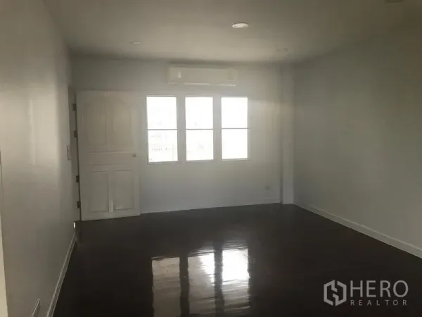 带办公室的家 出租或出售在Watthana, Bangkok - 宽敞房间，亮面木地板，窗上方挂壁空调与白色房门。