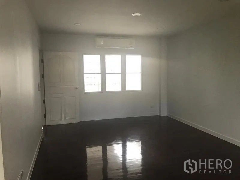 带办公室的家 出租或出售在Watthana, Bangkok - 宽敞房间，亮面木地板，窗上方挂壁空调与白色房门。