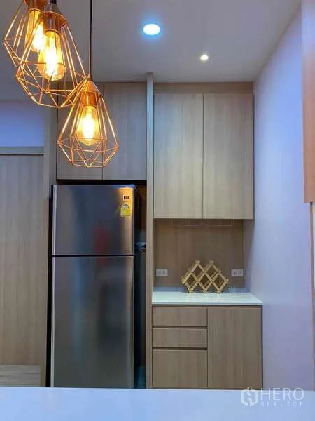 Townhouse for rent - Kitchen close-up showing stainless refrigerator, tall built-in cabinets and geometric pendant lights.