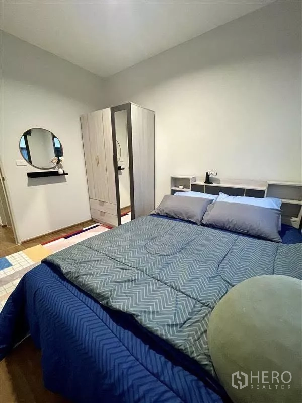 Townhouse for rent in Samut Prakan - Bedroom from another angle showing bed, full-length mirror and storage wardrobe.